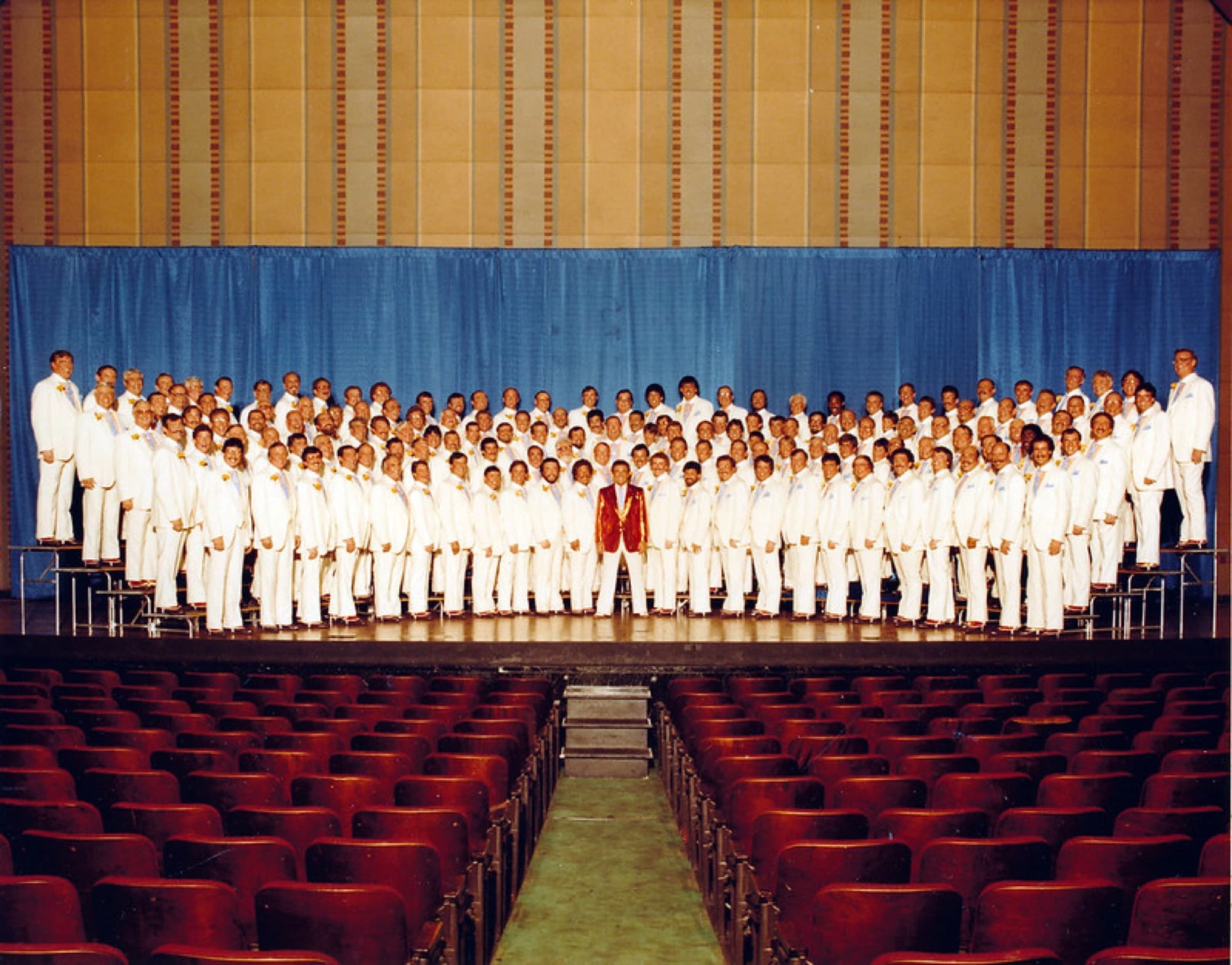 The Big Apple Chorus on stage in white tuxedos, 1984.